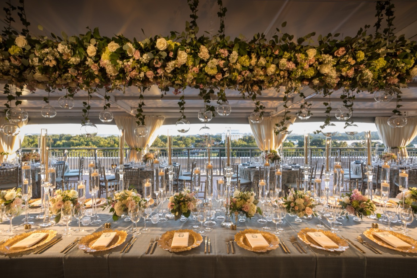 Rooftop tent reception with a suspended rose and hydrangea installation over long tables