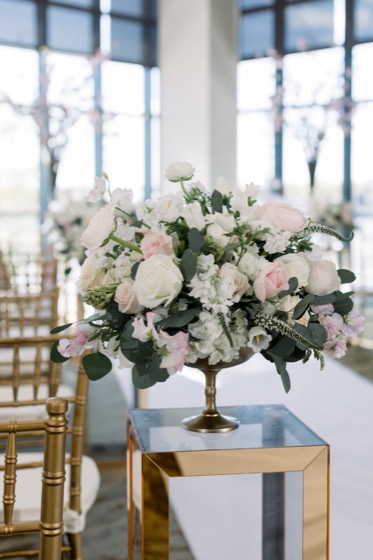 Blush and ivory roses in a brass compote on a gold mirrored pedestal