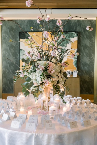 Cherry blossom branches in a gold vase above an escort card table