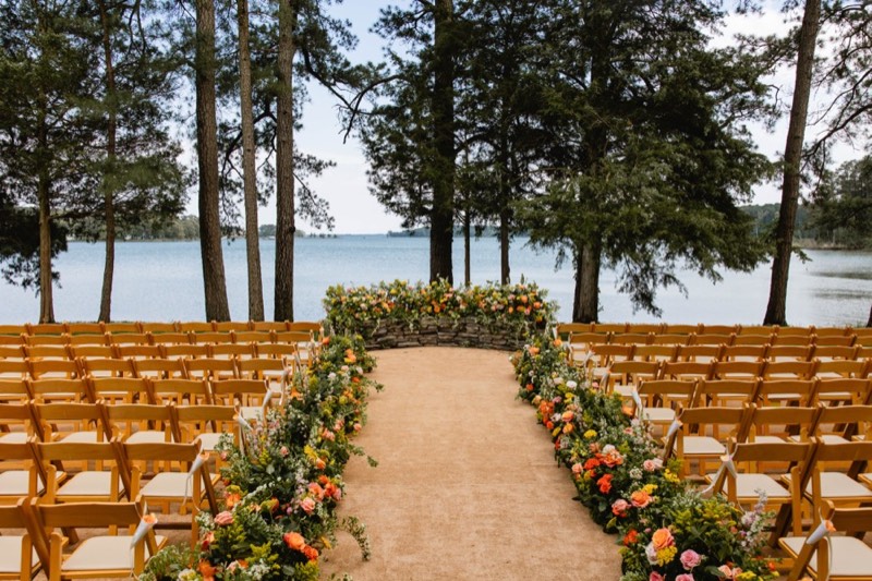 Lakeside ceremony aisle lined with coral and orange florals