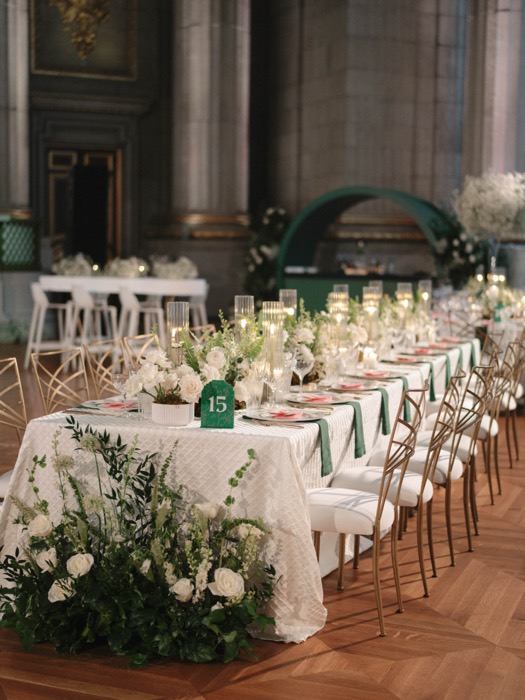 Emerald and white tablescape with gold chairs in a stone ballroom