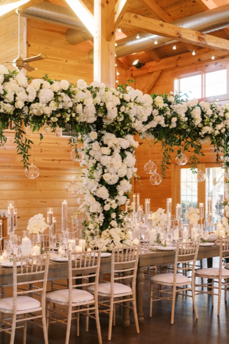 Suspended white hydrangea installation over a barn reception table
