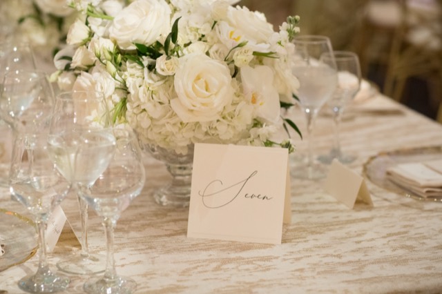 White rose and orchid centerpiece with a calligraphed table number